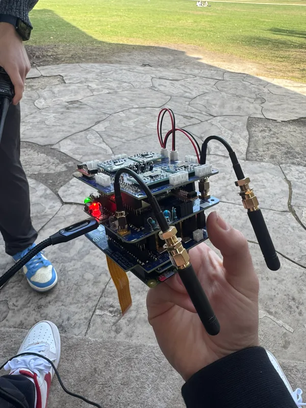 Hand-held AMSAT avionics stack with connected antennas and illuminated indicators.