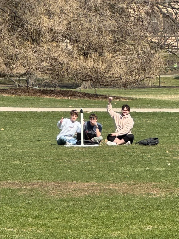 Three SRG team members outdoors beside ground-station equipment during testing.