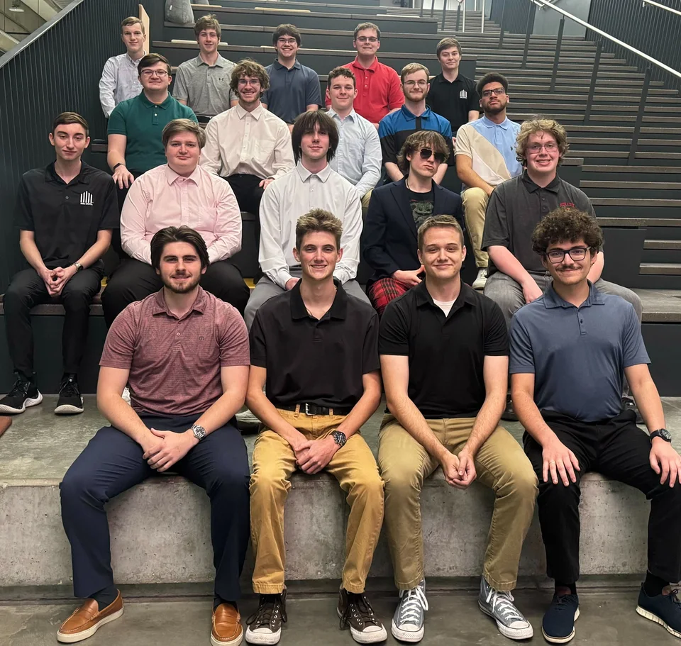 SRG members seated together on the steps of an indoor staircase for a group photograph.